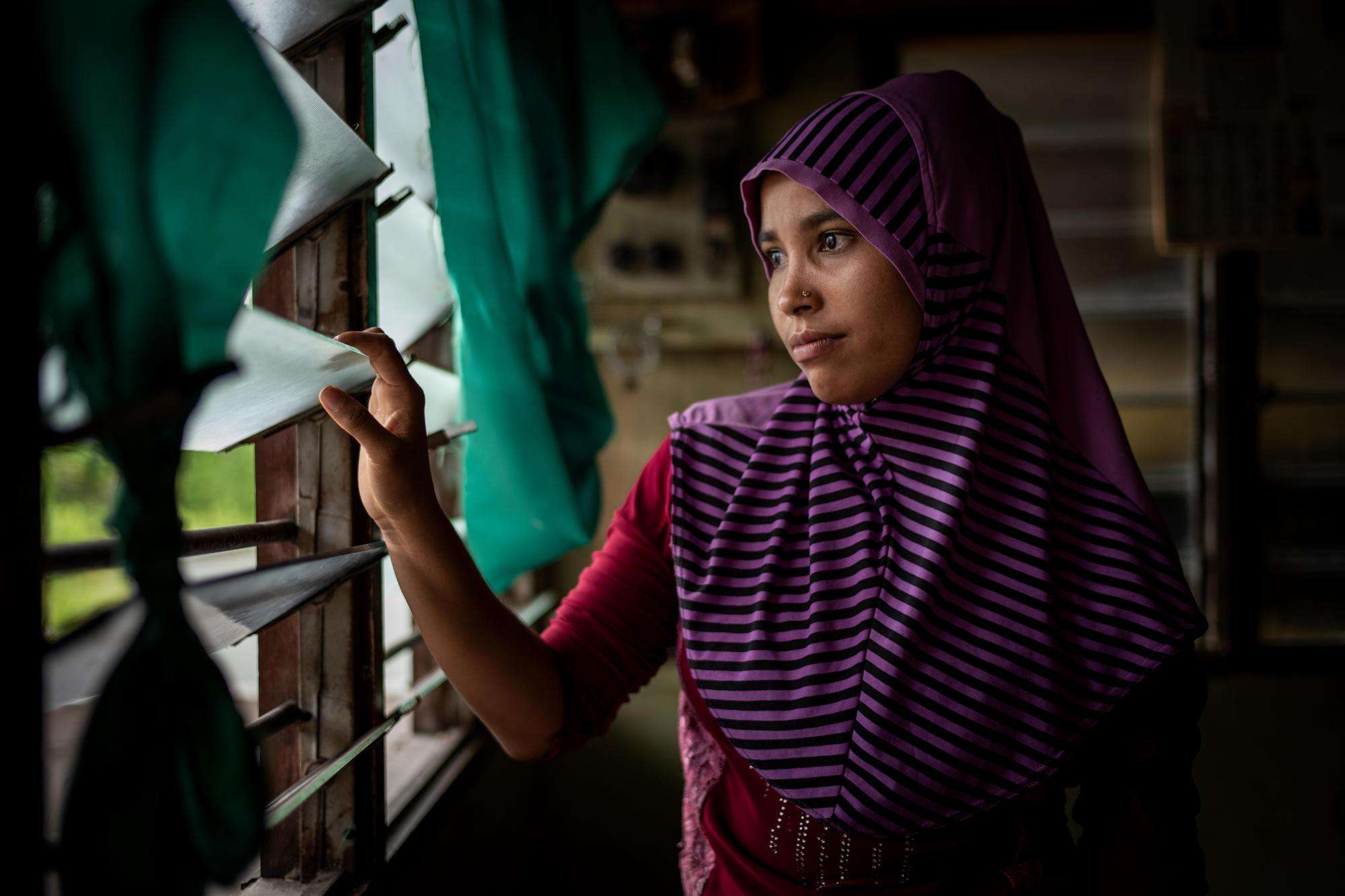 A Rohingya refugee looks out of her window in Malaysia