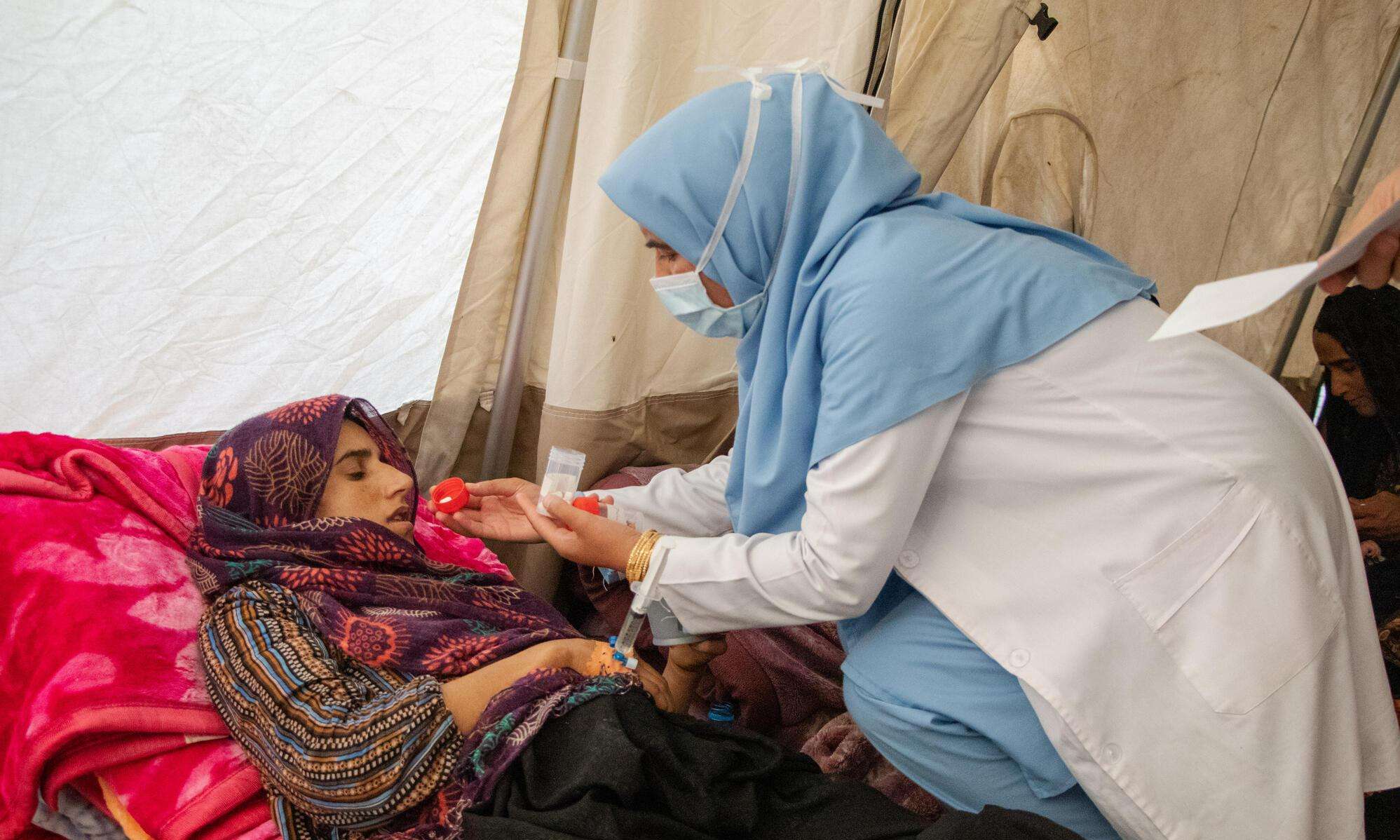 A female nurse gives an injured woman medication in an MSF emergency tent after the Afghanistan earthquake.