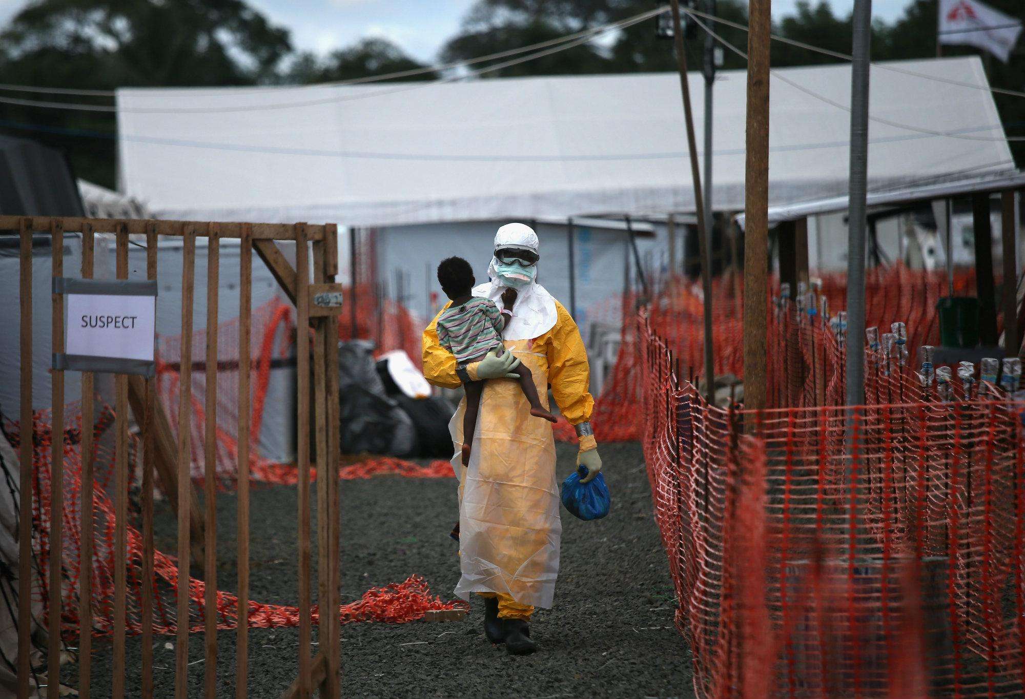 An MSF health worker carries a child suspected of having Ebola.