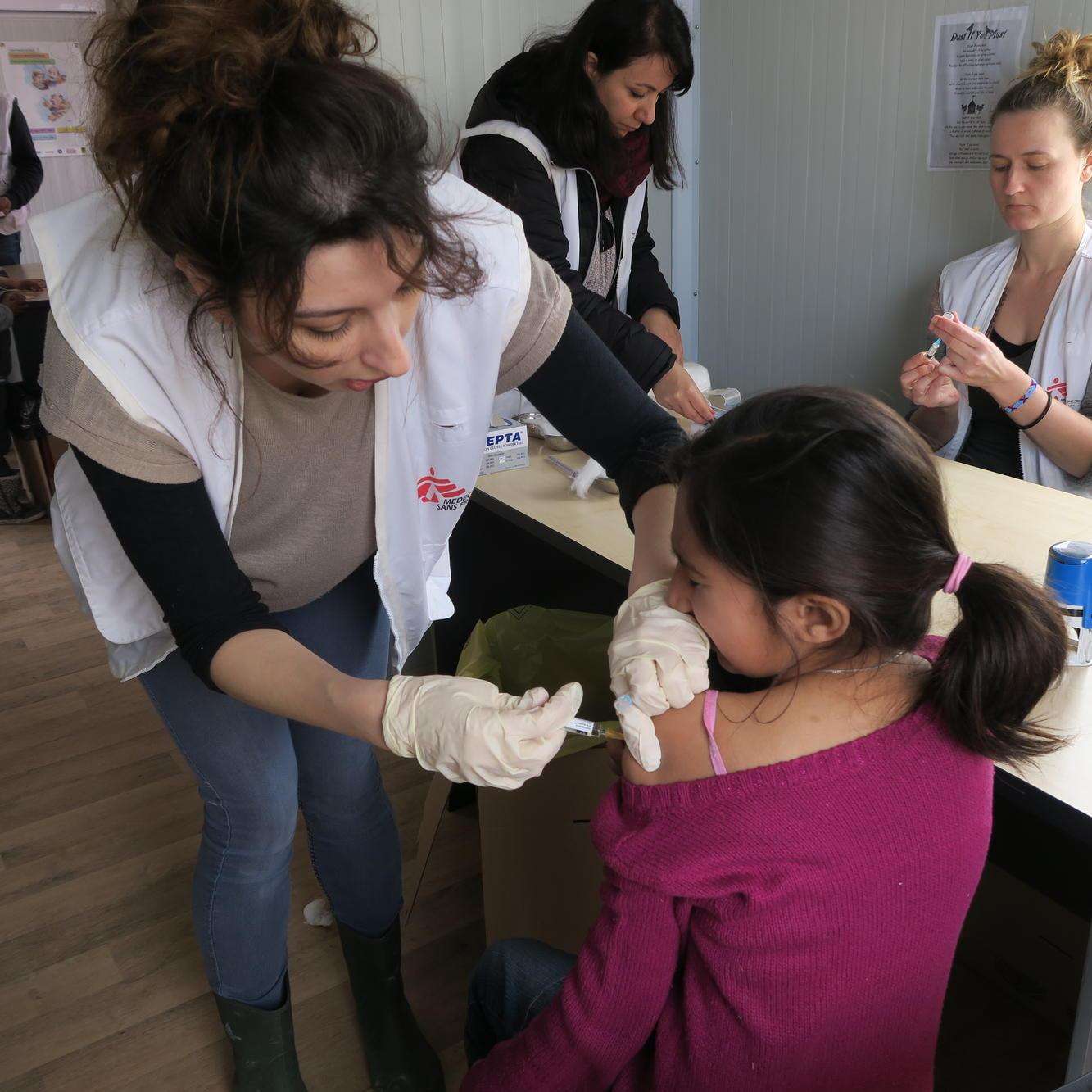 MSF nurse Persa Dimitsaki vaccinates a child during an emergency measles vaccination campaign in Moria camp on the Greek island of Lesvos
