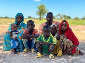 A refugee family from Sudan sits on the grass outside Wedweil camp in South Sudan.