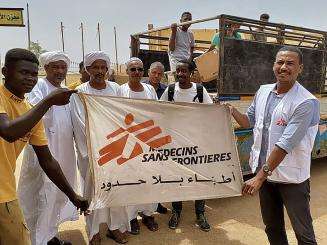 Dr. Mohammad Bashir holds an MSF flag with others in Sudan.