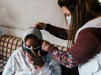 Medic putting a mask on a woman in her home