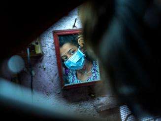 Mirror of a woman wearing a surgical face mask in Mumbai, India.