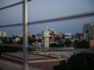 View of an urban landscape in Sudan through the bars of a fence.