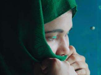 Profile of a young Rohingya woman in a green headscarf in Bangladesh.