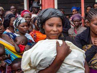 A Congolese woman holding a baby wrapped in a blanket in DR Congo.