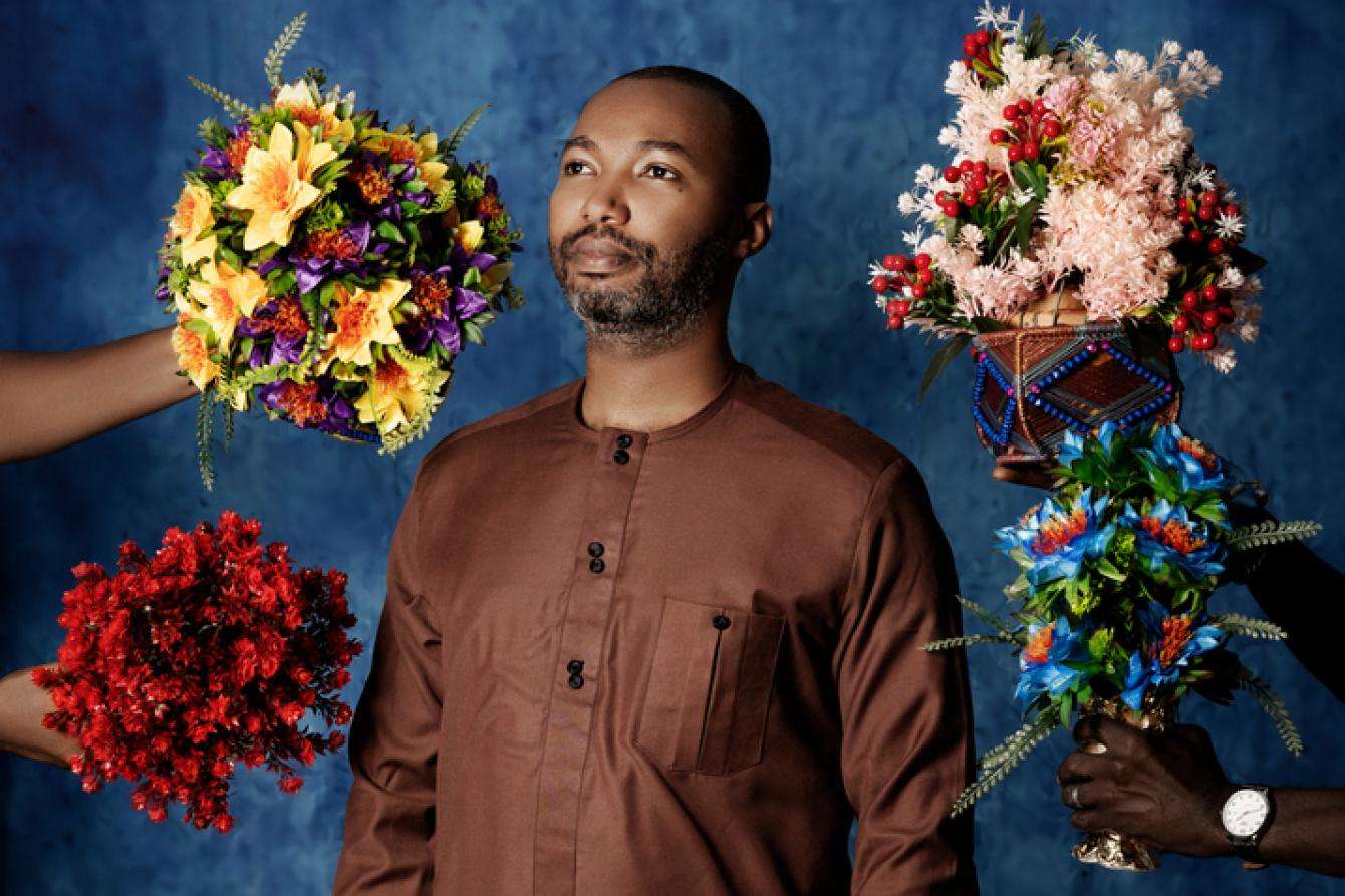 An MSF doctor in Guinea surrounded by four bouquets of flowers.