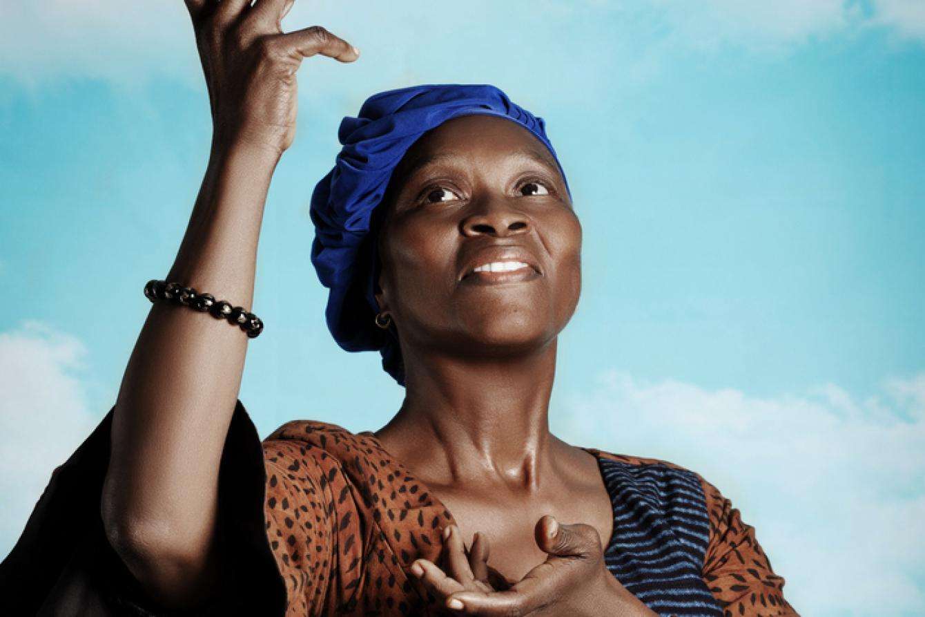 A woman with hands in the air against sky blue background.