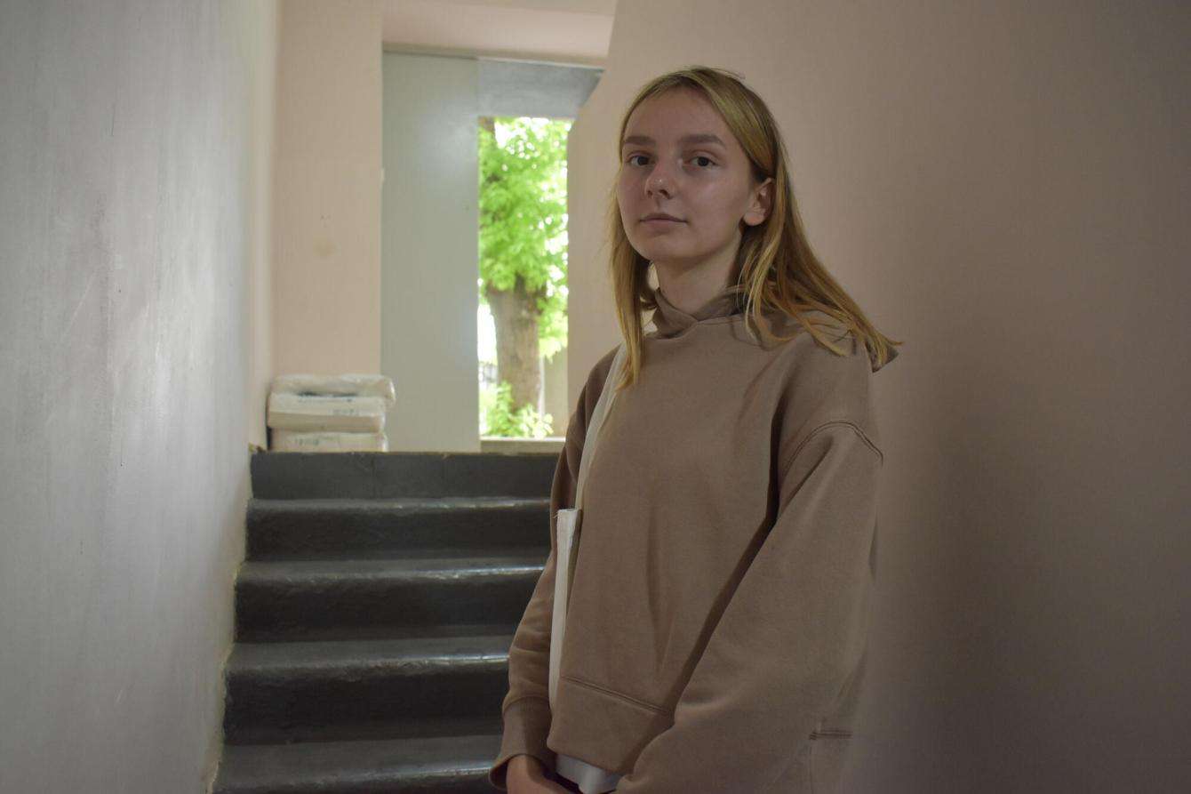 A blond woman standing in a stairwell of a building in Belgorod where MSF offers mental health support.