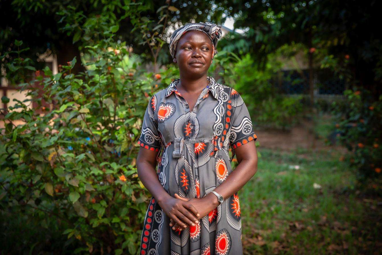 Woman in colorful dress standing in front of a green area in the Central African Republic