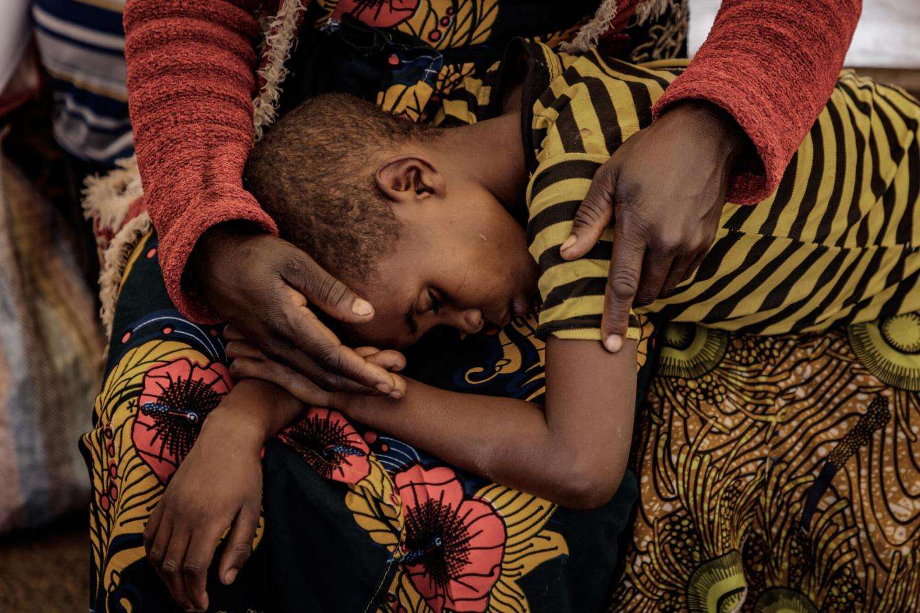 A child lays on the lap of her mother at MSF's cholera treatment unit in Democratic Republic of Congo.