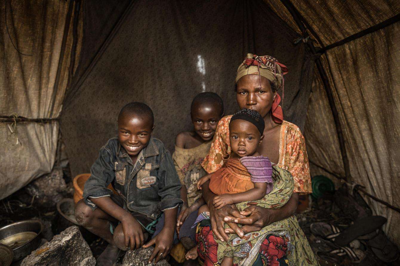 Foibe Bonane with her three children inside their tent in Rusayo camp