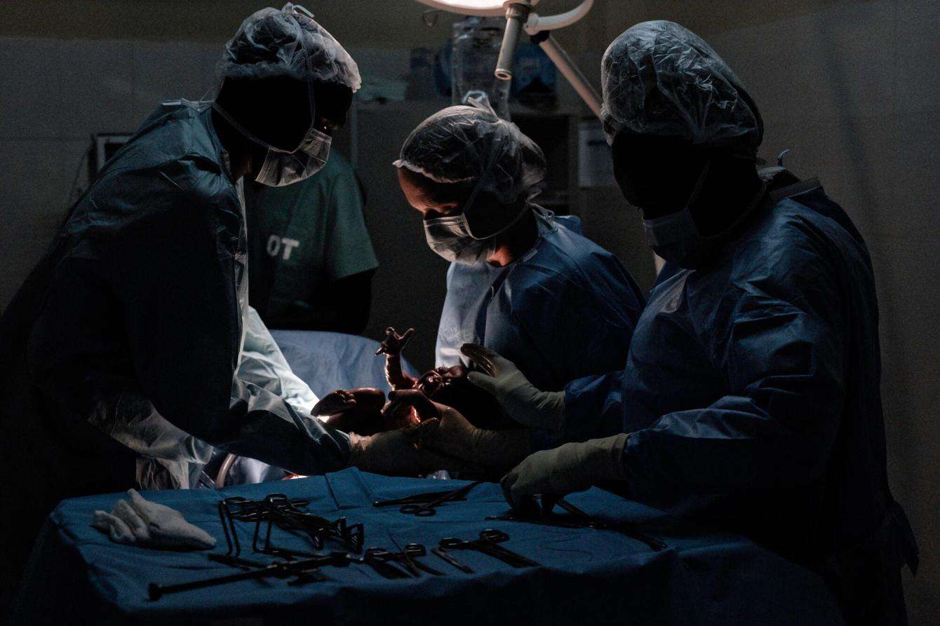 Surgeons deliver a baby in a dark room in Abyei, South Sudan