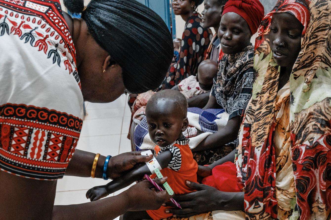 Malnutrition screening of one-year-old Alnel on the knees of his mother Nyanbeny. Ameth Bek Hospital, Abyei.