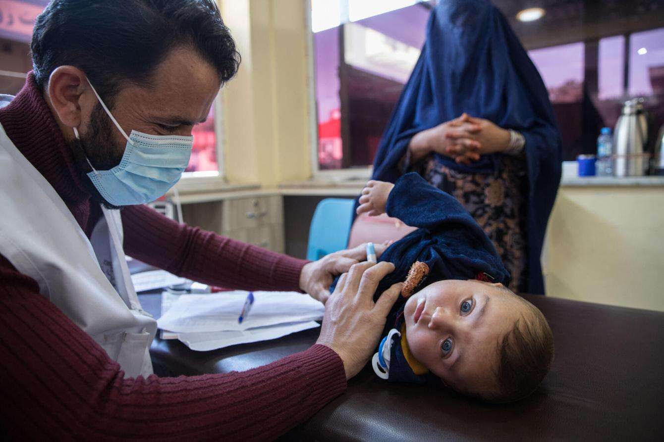 An MSF doctor checks a child patient with the mother watching in Afghanistan.