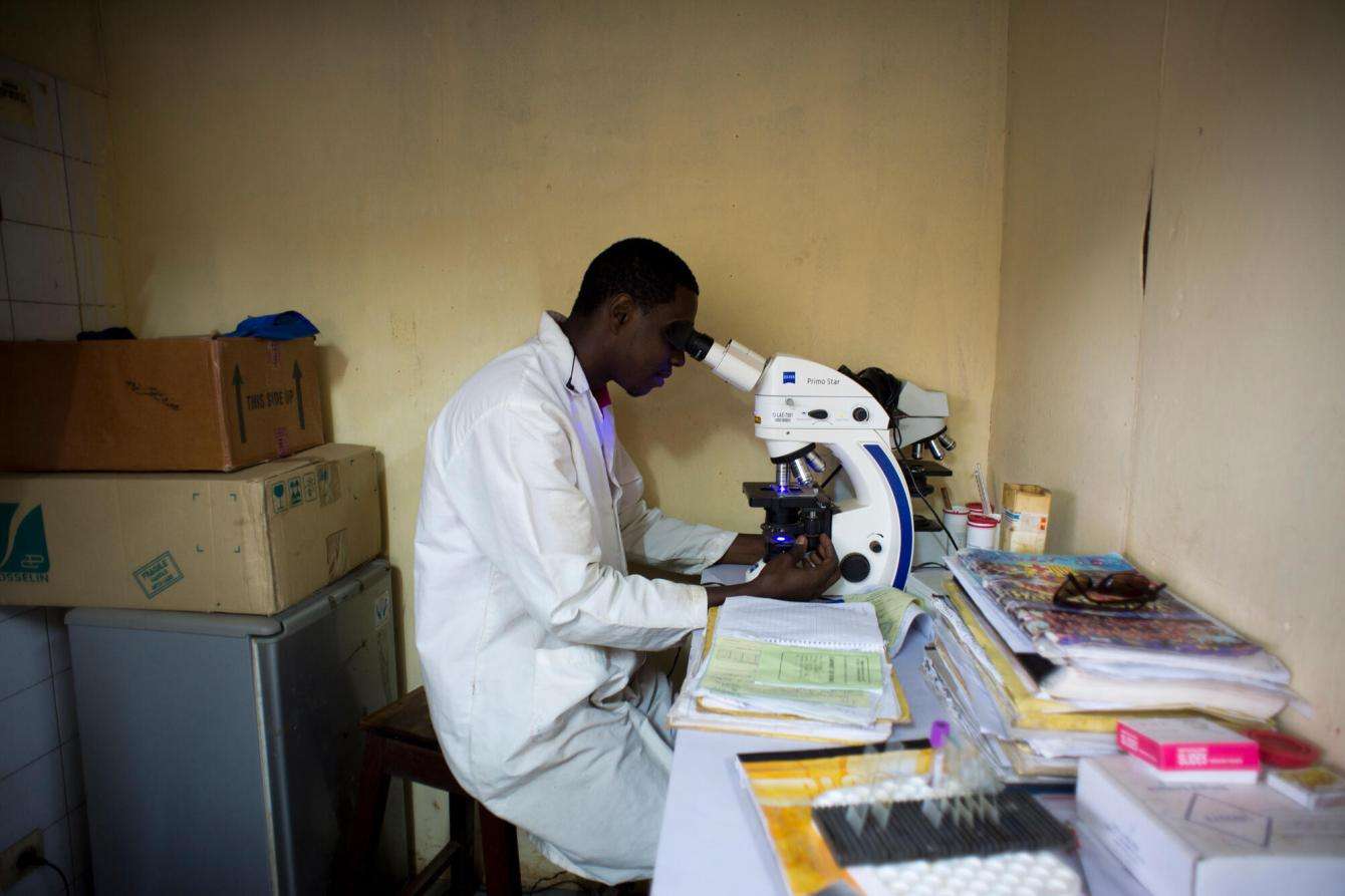 A laboratory technician looks into a microscope at the MSF labratory in Matam, Guinea.