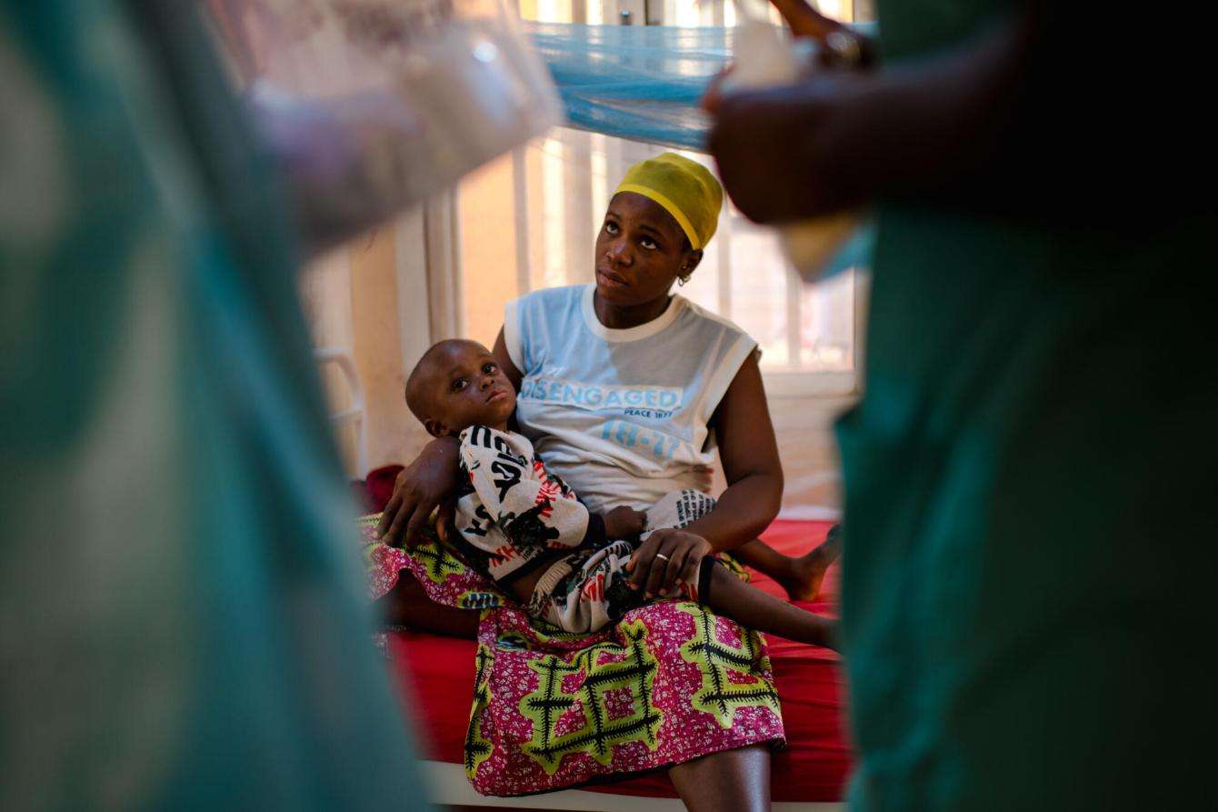 A mother holding her child at a diphtheria treatment center in Siguiri, Guinea