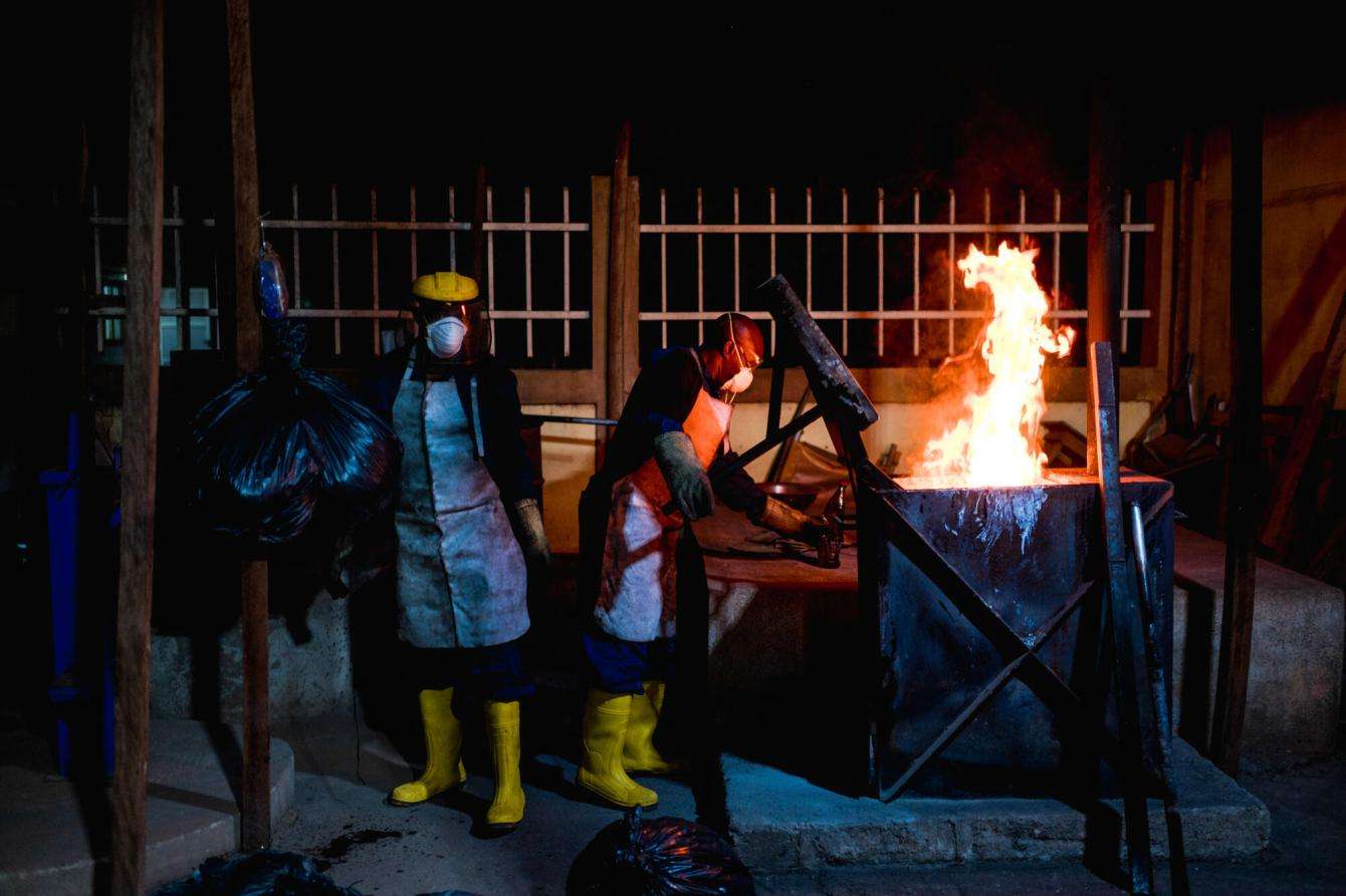 The sanitation crew burns garbage in the evening at the treatment center for diphtheria in Guinea.