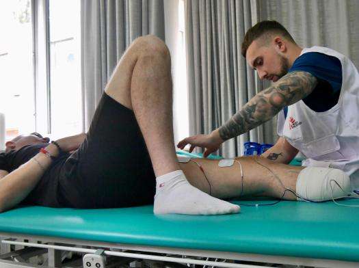 An MSF physiotherapist treats a war-wounded patient during a treatment session in Ukraine.