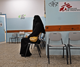 A veiled woman waits in a chair at an MSF facility in Gaza.