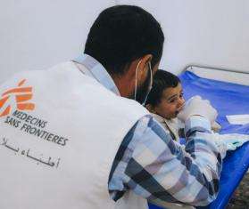 MSF aid worker in white vest treats child patient for cholera