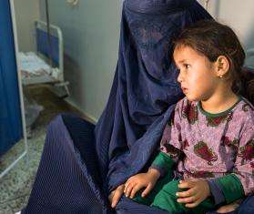 An Afghan mother in a burqa holding her child at Mazar-i-Sharif Regional Hospital in Afghanistan.